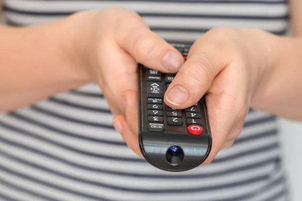Remote control in female hands pointing to TV Stock Photo