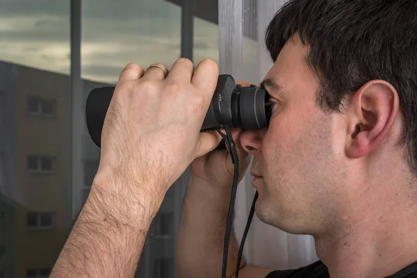 Man is spying his neighbours with binoculars — Stock Photo, Image