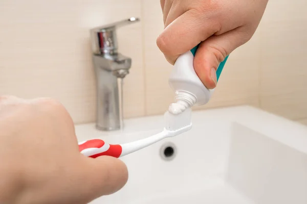 Extrusion of toothpaste on the brush in the bathroom — Stock Photo, Image