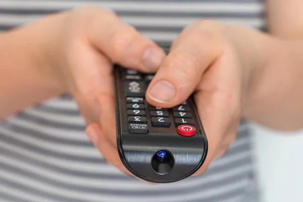 Remote control in female hands pointing to TV — Stock Photo, Image