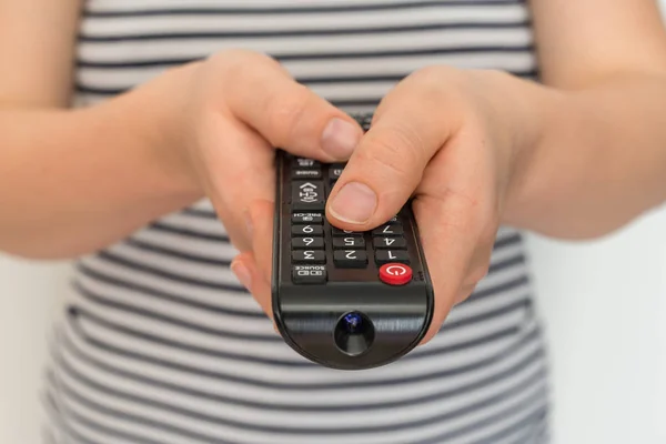 Remote control in female hands pointing to TV Stock Image