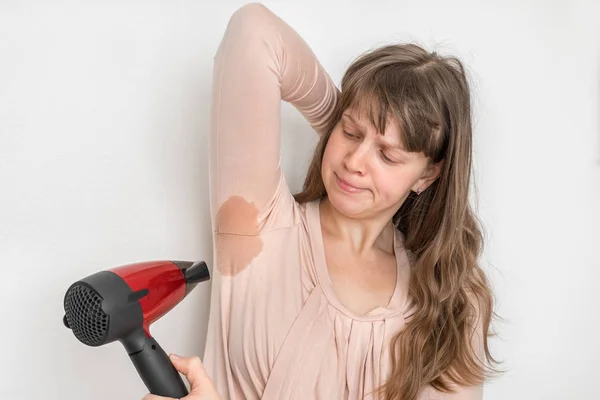 Woman is drying her sweating armpit with hair dryer — Stock Photo, Image