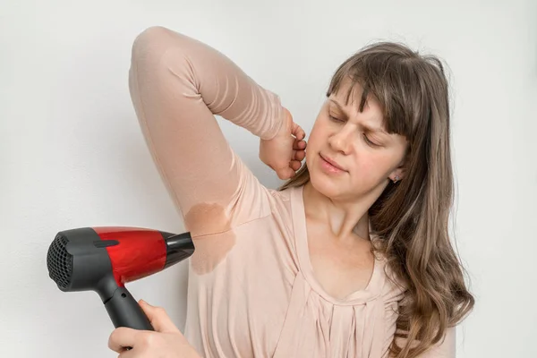 Vrouw is haar zweten oksel met een föhn drogen — Stockfoto