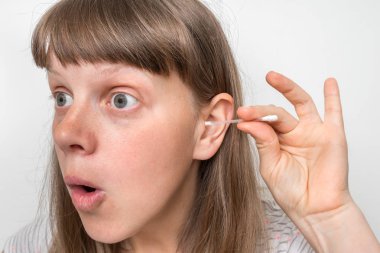 Kadın kirli kulaklarını pamukla temizliyor.