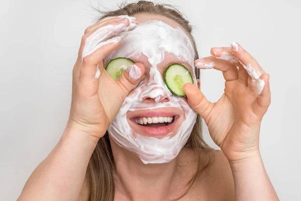 Mujer con máscara de crema natural y pepinos en la cara — Foto de Stock