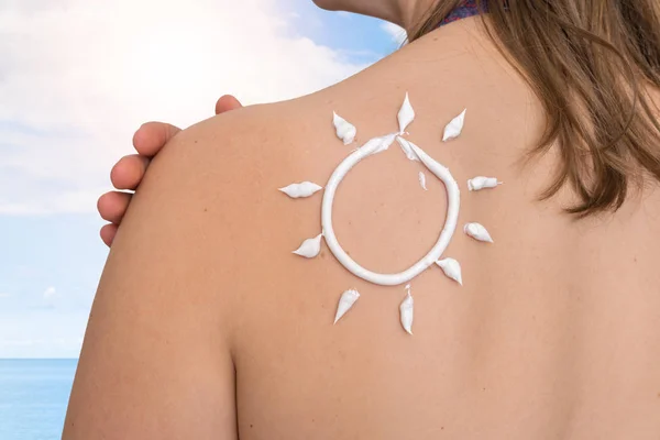Frau mit Sonnencreme auf der Schulter in Sonnenform — Stockfoto