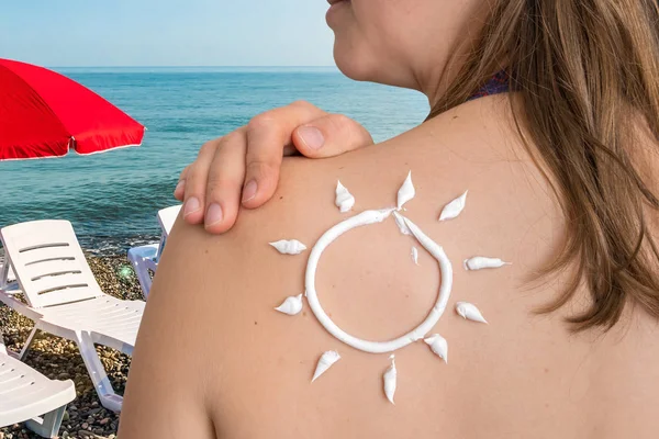 Vrouw met zonneproducten lotion op haar schouder in de vorm van de zon — Stockfoto