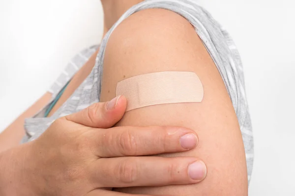 Woman with adhesive bandage on her shoulder