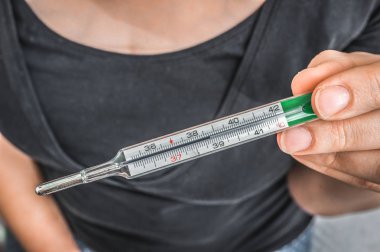 Kadın ateşle Merkür termometre tutuyor