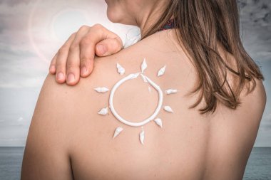 Güneş şeklinde omzunda güneş losyonu olan kadın