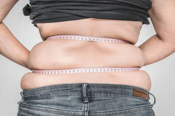 Overweight woman with tape is measuring fat on belly