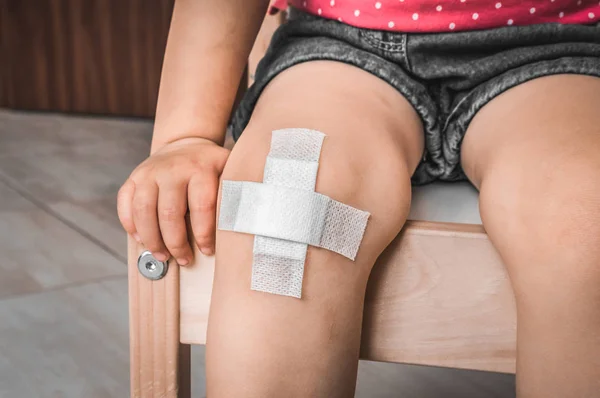 Niño con vendaje adhesivo en la rodilla —  Fotos de Stock
