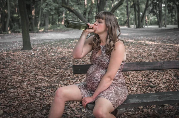 Terhes nő iszik bort a parkban-alkoholizmus koncepció — Stock Fotó