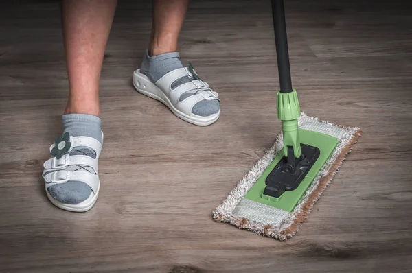 Mulher com esfregão esfregando piso laminado de madeira — Fotografia de Stock