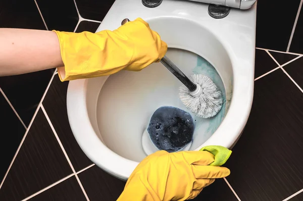 Woman is cleaning toilet bowl using brush — Stock Photo, Image