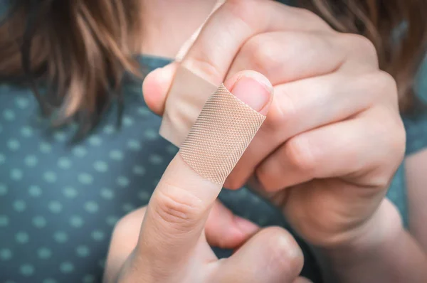 Donna mette un cerotto sul dito ferito — Foto Stock