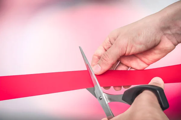 Hand with scissors cutting red ribbon - opening ceremony