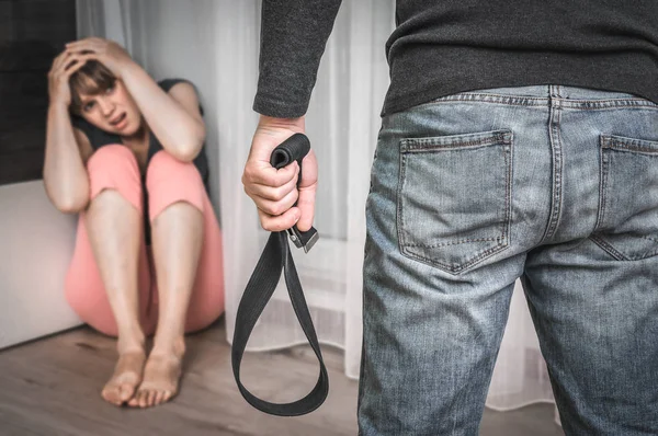 Uomo con una cintura che picchia la moglie - violenza domestica — Foto Stock