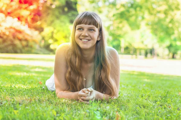 Joven hermosa mujer en vestido blanco acostado en la hierba — Foto de Stock