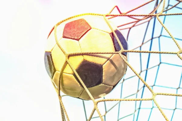 Soccer ball in the goal net with blue sky background