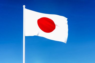 Mavi gökyüzü arka plan üzerinde Japonya bayrağı sallayarak