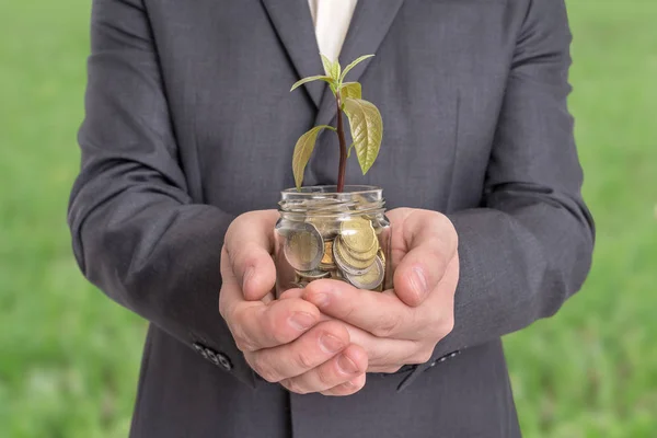 Podnikatel drží skleněnou sklenici s málo rostlina roste na mo — Stock fotografie