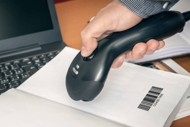 Tarayıcı tarayıcısı olan adam kitaptaki barkodu tarıyor.