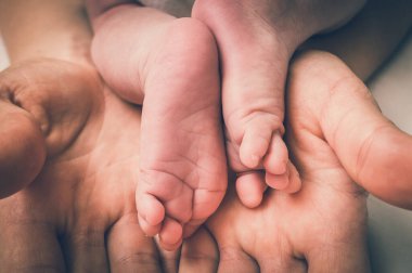 Yeni doğmuş bebek ayakları annenin ellerinde - aile sevgisi konsepti - retro tarzı