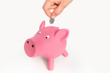 Kadının eli pembe domuz kumbarasına para yatırıyor - finans konsepti