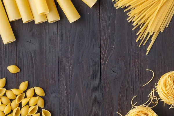 Raw pasta on rustic dark wooden background