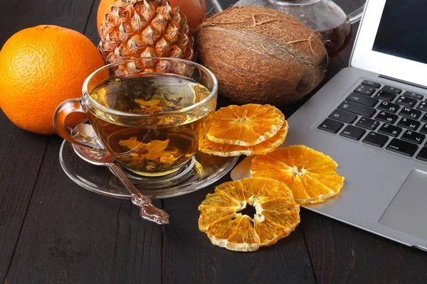 Teapot with black tea, roses, oranges and grapefruit on light background