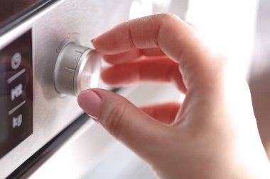 Döndürme tutan el daire düğmesi ısı odasında Gıda Mutfak Ev, Closeup yemek pişirmek için mikrodalga fırın çevir.