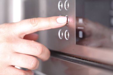 Mutfakta taze kurabiye pişirme için mikrodalga fırın kullanan kadın