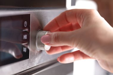 Mutfakta taze kurabiye pişirme için mikrodalga fırın kullanan kadın