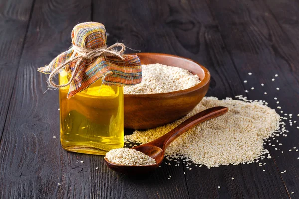 Sesame oil in a bottle and sesame seeds in the cup - a source of vitamin E, calcium, phosphorus