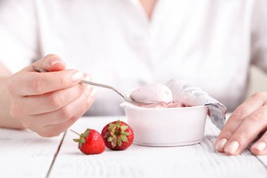 Çilekli sütlü kaşık el ile beyaz tabloda krem