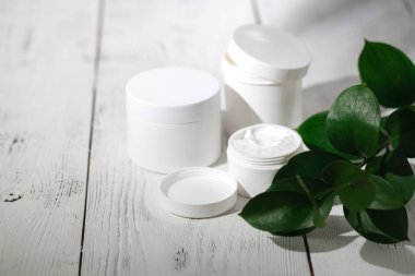 Kozmetik şişe kapları ile yeşil bitki yaprakları, marka mock-up, doğal organik güzellik ürün kavramı için boş etiket paketi