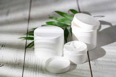 Kozmetik şişe kapları ile yeşil bitki yaprakları, marka mock-up, doğal organik güzellik ürün kavramı için boş etiket paketi