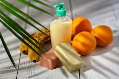 Kozmetik şişe kapları ile yeşil bitki yaprakları üzerinde beyaz ahşap masa