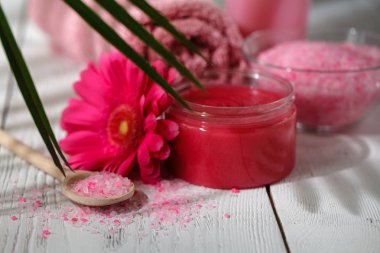 Kozmetik şişe kapları ile yeşil bitki yaprakları üzerinde beyaz ahşap masa