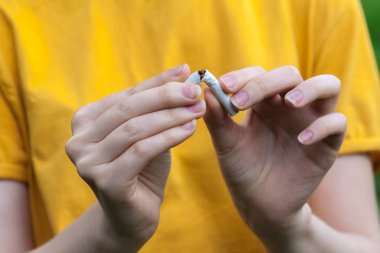 Sigara içmeyi bırak. Elinde kırık sigarayla gülümseyen güzel bir kızın portresi. Mutlu kadın sigarayı bırakıyor. Kötü alışkanlığı, sağlık hizmetleri konseptini bırak. Sigara içme..