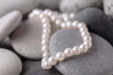 Yeşil taşların üzerinde inci kolyeler ve küpeler vardı.