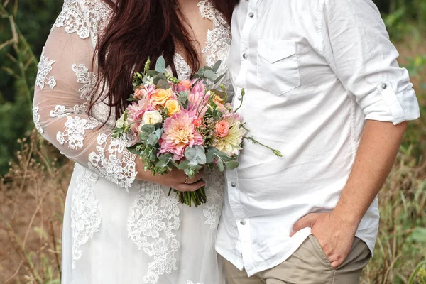 Artı boyutu evlilik çift ayakta ve dışında sarılma. Curvy gelin güzel renkli buket tutuyor. Gelin ve damat yaz yeşil aşk hikayesi.