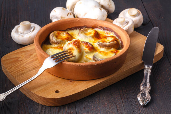 Georgian cuisine: Close up mushrooms baked with cheese suluguni on ketsi