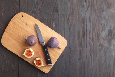 Sulu taze bütün incir meyve ve koyu arka plan üzerinde ahşap kesme tahtası üzerinde bir kesim incir