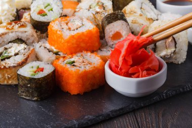 İki çubuk hosomaki tutan sebze ile rulo ve deniz ürünleri ile farklı suşi rulo 
