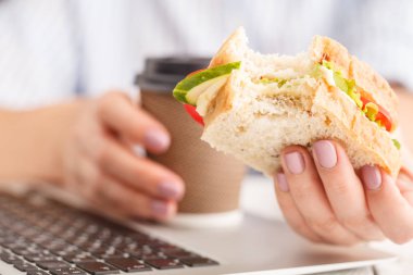Kahvaltı sandviç yeme ve içme kahve ile bir dizüstü bilgisayar çalışırken kadın