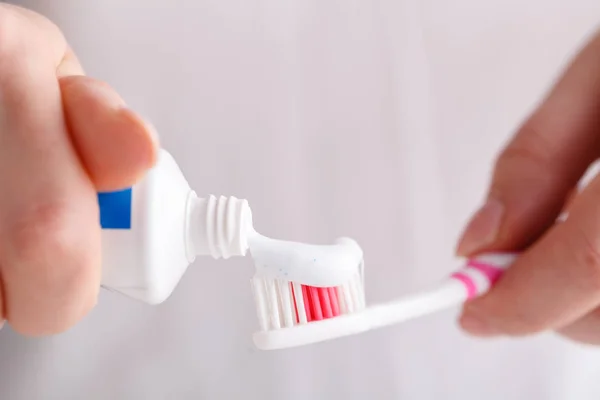 squeezing toothpaste from tube on modern toothbrush close up
