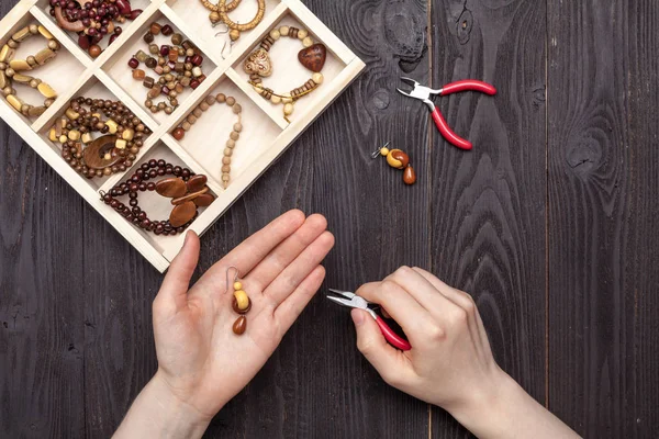 Trabajo a mano en casa, la chica hace joyas manos sobre la mesa —  Fotos de Stock