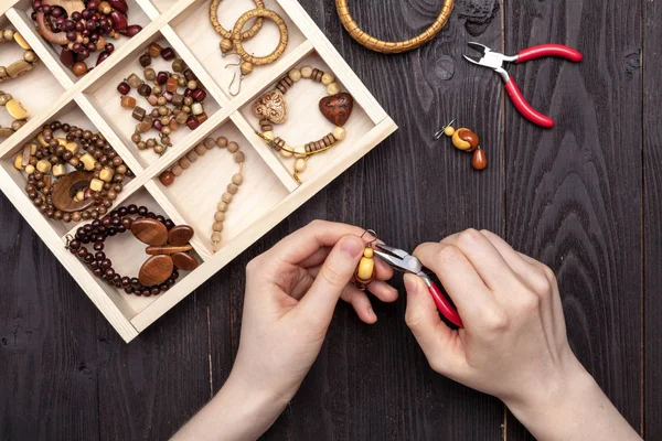 Trabajo a mano en casa, la chica hace joyas manos sobre la mesa — Foto de Stock